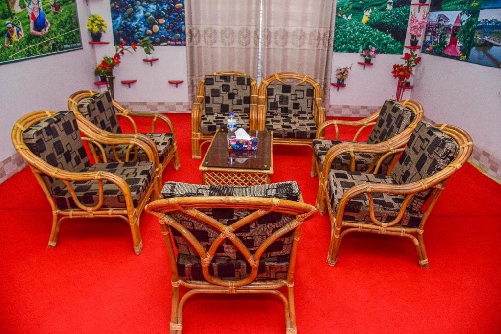 Lounge seating area at Al Hera Resort with woven rattan armchairs around a glass-top table, red carpet, and tea-garden themed wall photos