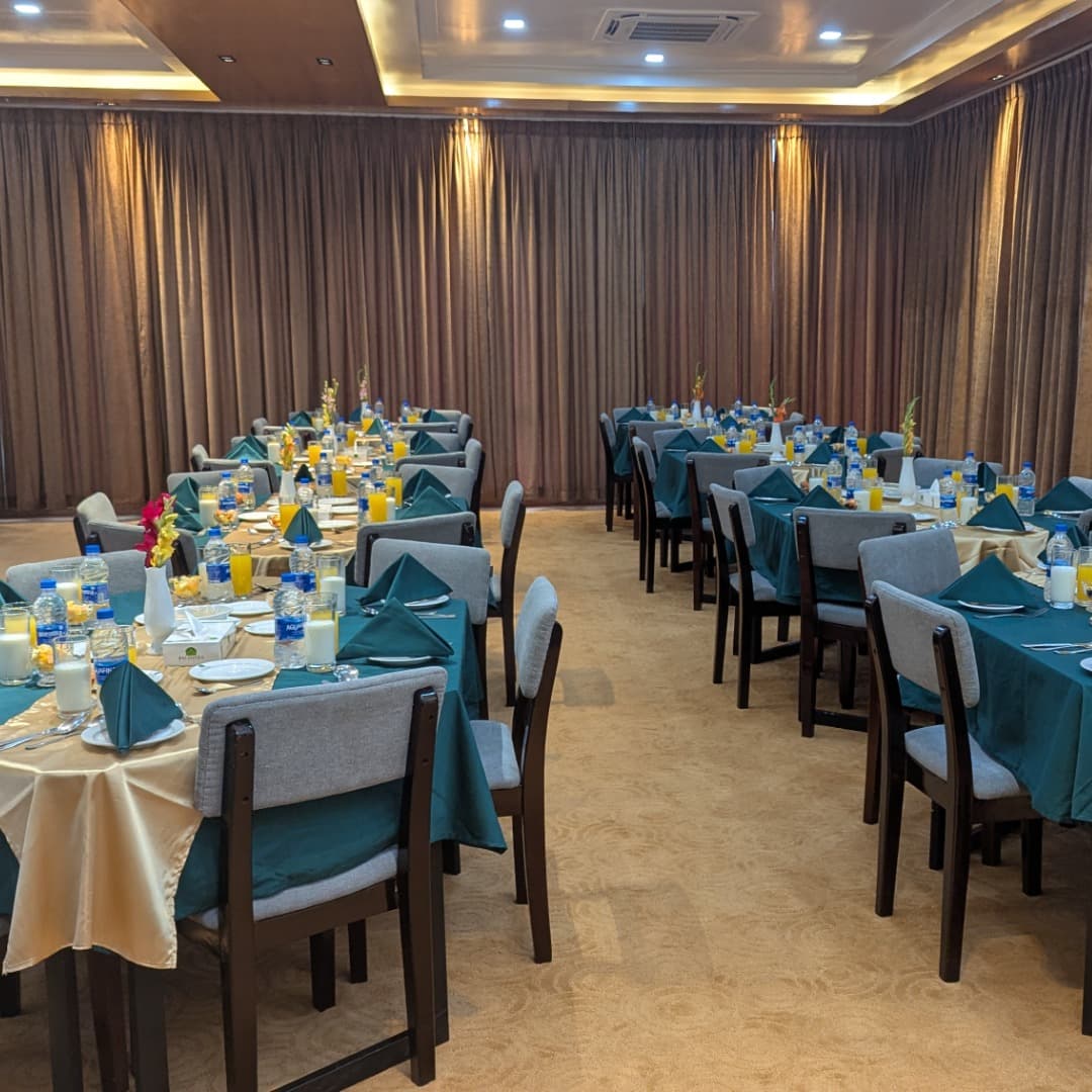 Balishira Resort's banquet dining hall set for a group meal, teal napkins and gold tablecloths at rows of tables