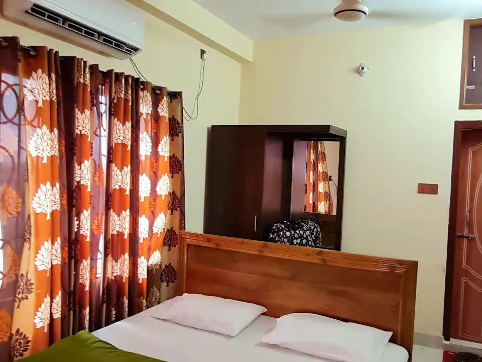 A double room at Cha Luxury Hotel & Restaurant with a wooden headboard, patterned curtains, and a wardrobe with mirror