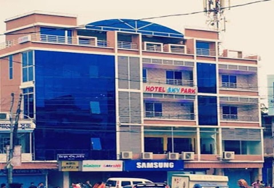 Hotel Skypark's street-facing building with its illuminated sign and blue-domed rooftop above a Chaumuhani storefront