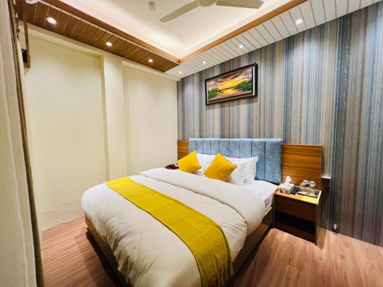 Hotel Taj Metro guest room with a double bed and yellow accent pillows