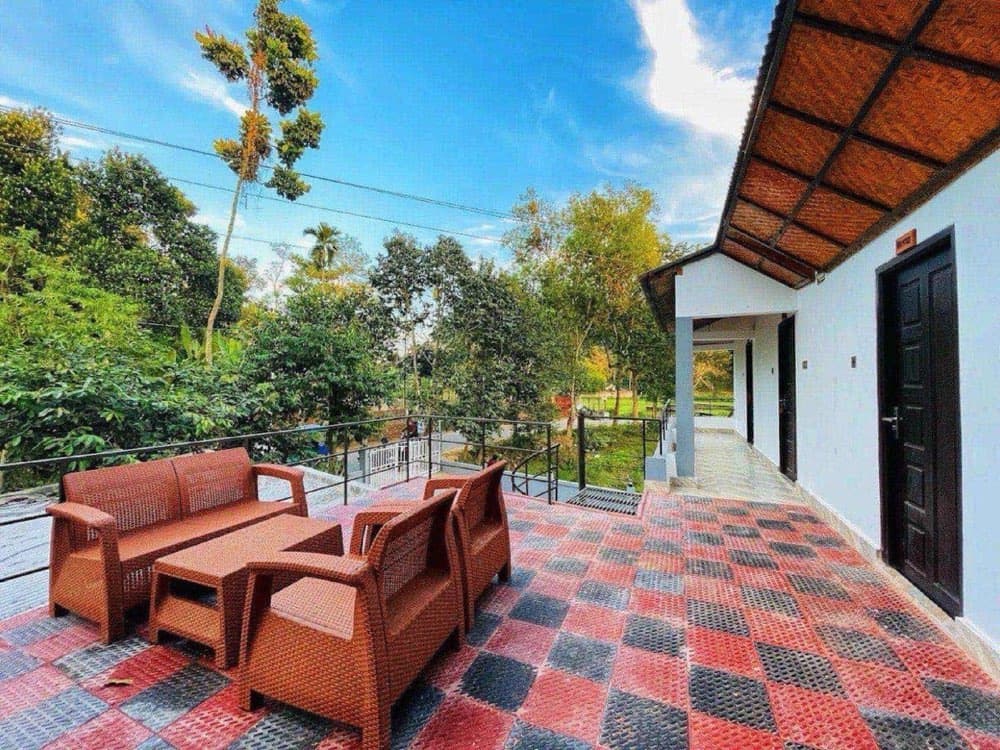 A terrace with rattan furniture overlooking greenery at Joldhara Resort