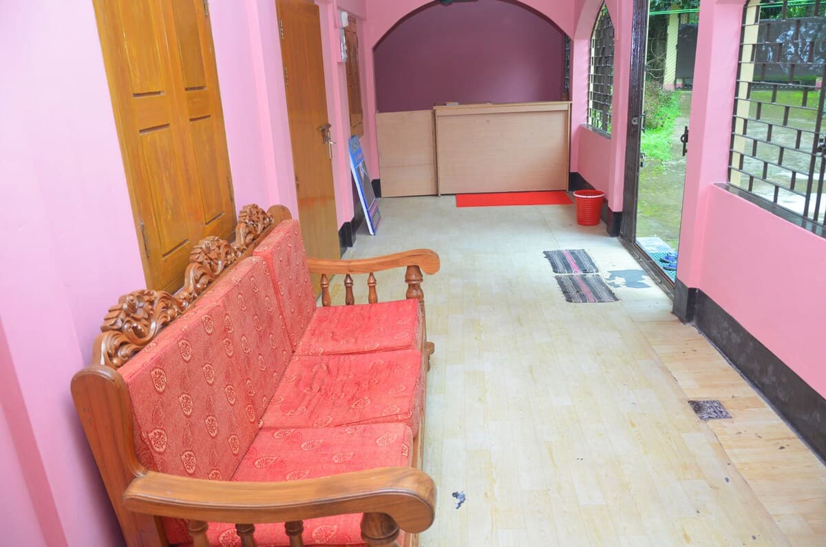 Reception hallway with a carved wooden sofa and pink walls leading to the front desk