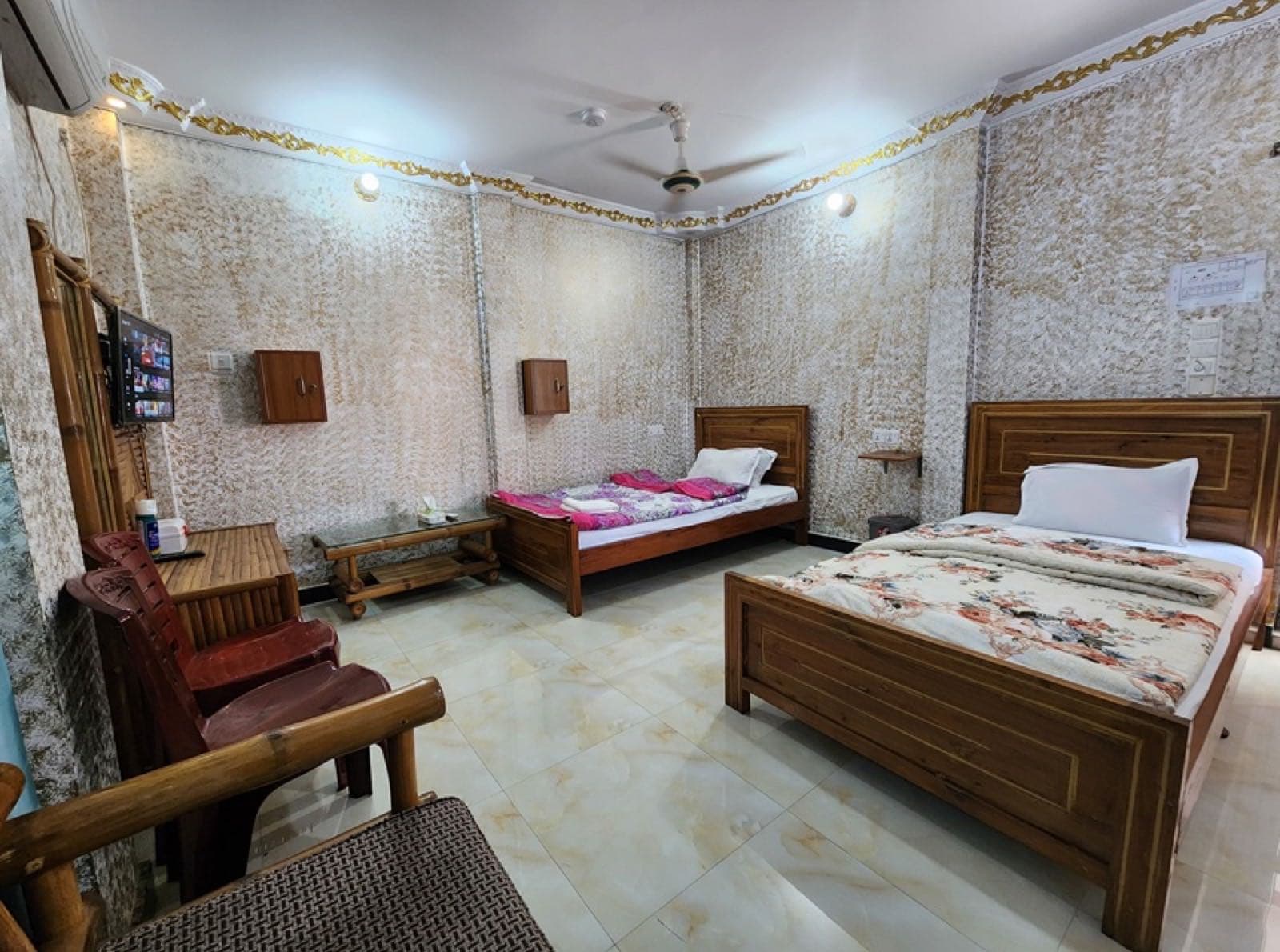 A twin-bed room at Mukta Nagar Resort with patterned wall panels and wooden furniture