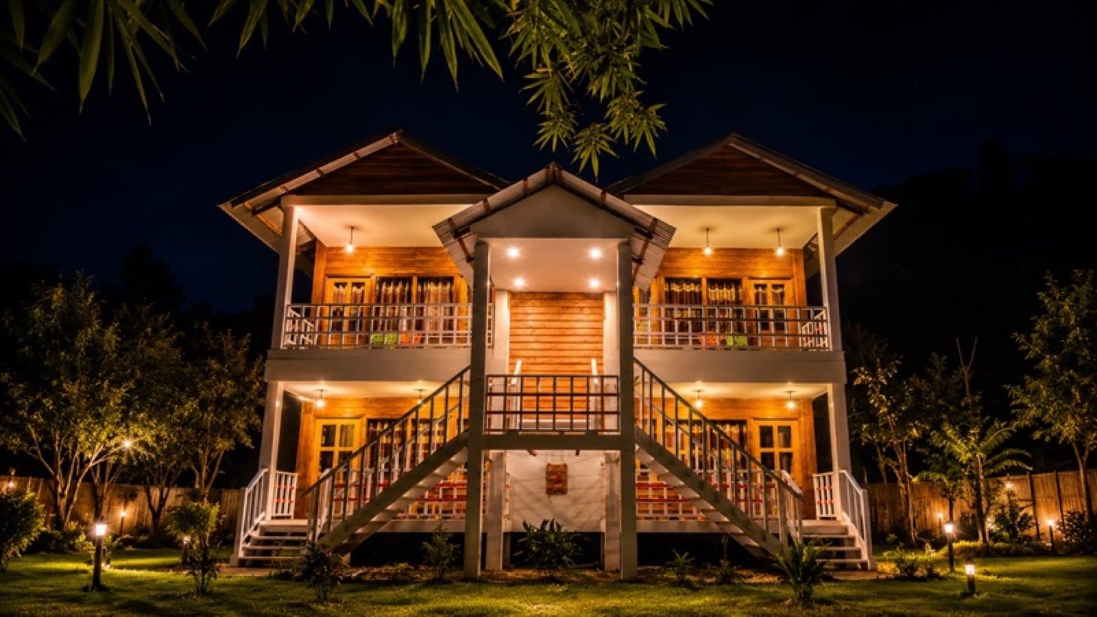 Nirban Nibash Resort's lit-up wooden cottage building with balconies at night