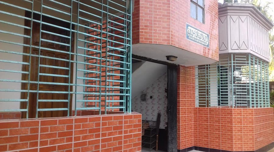 Paradise Lodge Guest House's brick entrance with grille-covered windows and a Bangla signboard above the doorway
