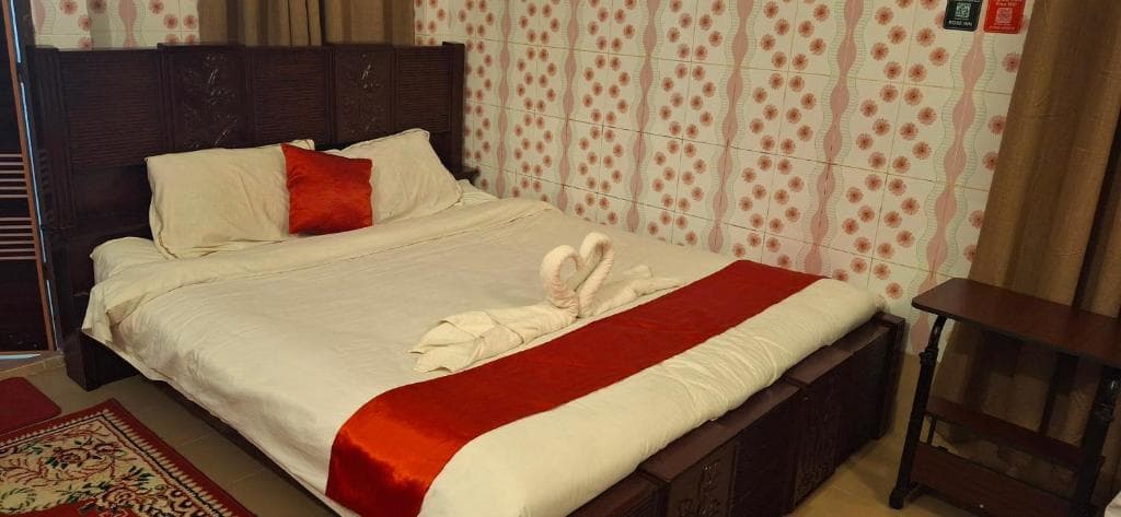 A double room at Rose Inn with a dark wood bed, white linen and a red runner, towels folded into swans