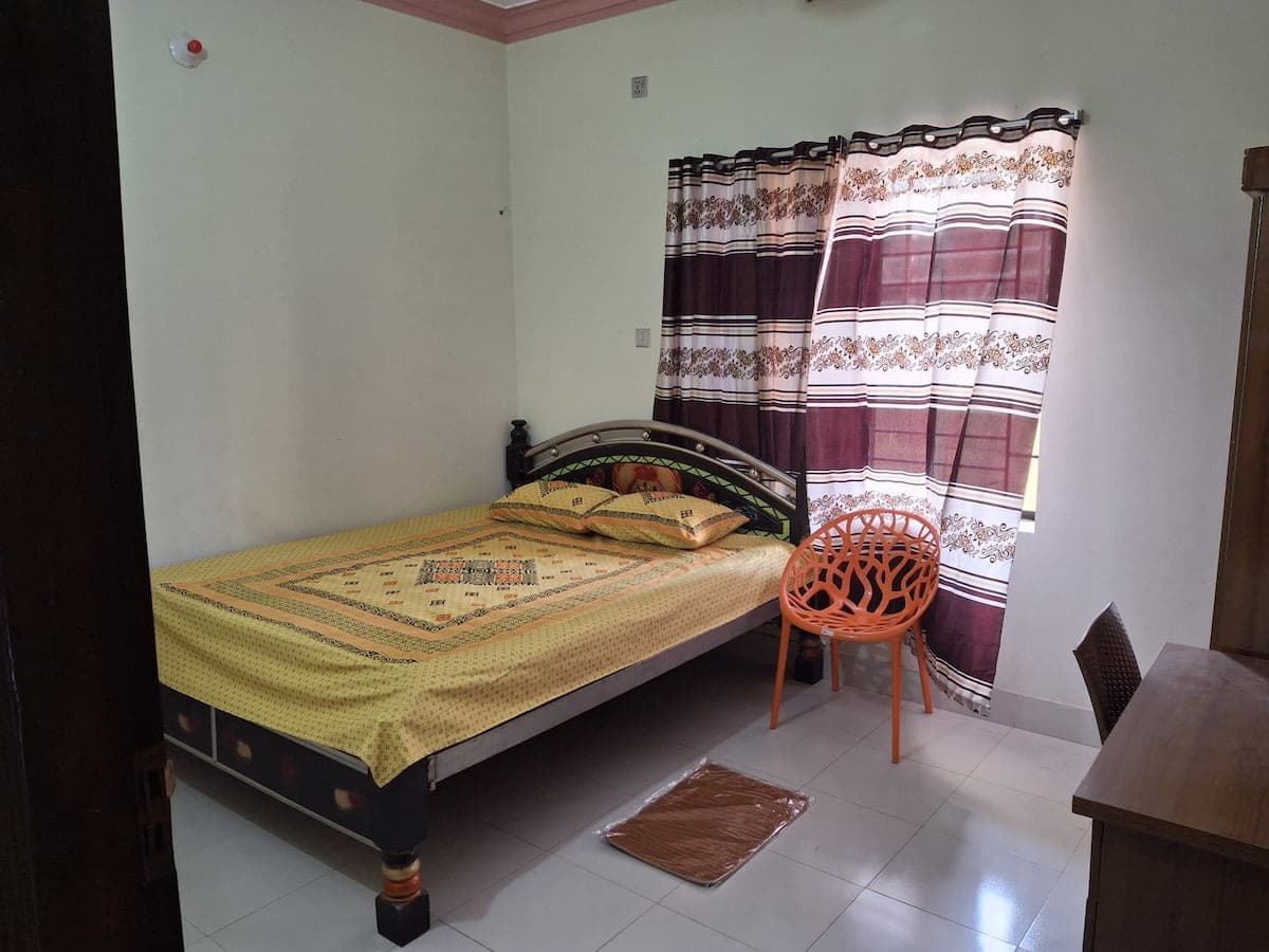 Second bedroom with single bed, yellow bedspread and orange accent chair