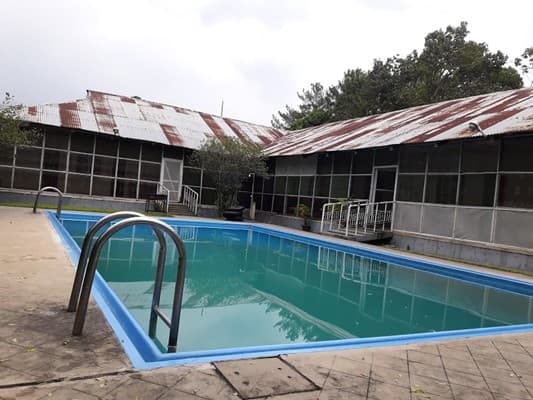 The corrugated rust-roofed bungalow wings of Sreemangal Tea Resort and Museum seen from beside the pool