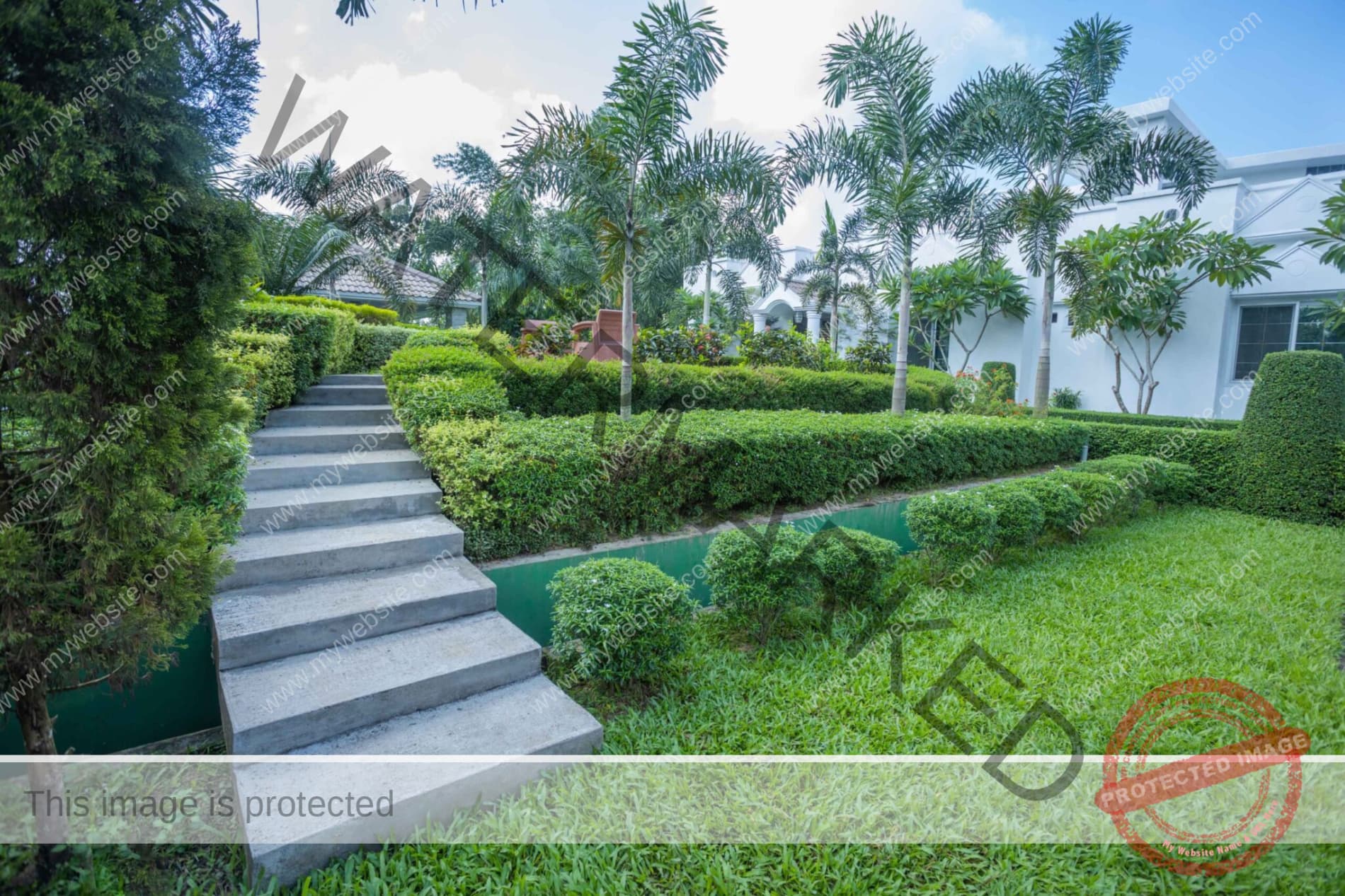 Concrete garden steps beside a water channel leading up to Tea Villa Luxury Resort's white arched building