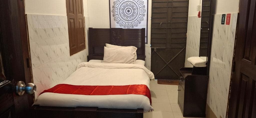 A compact single room at Rose Inn with a neatly made bed and folded towels